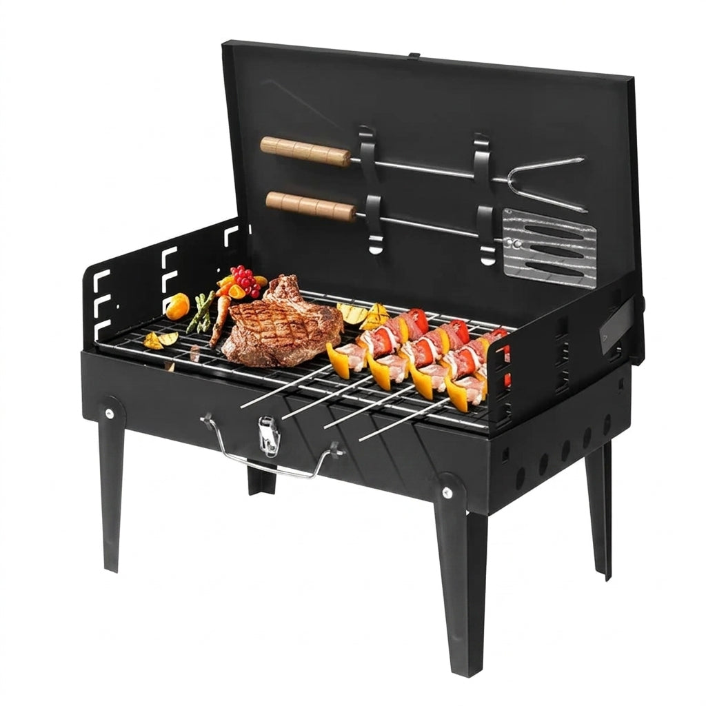 A black portable folding charcoal grill with its lid open, shown on a white background. The grill is set up with food, including a steak, skewers, and vegetables, and has utensils stored inside the lid.